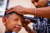Victor Moreno, 5, squints his eye as hair stylist Thomas Rose trims him up during a back-to-sch ...
