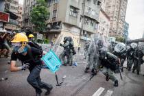 A protester flee from baton wielding police in Yuen Long district in Hong Kong on Saturday, Jul ...