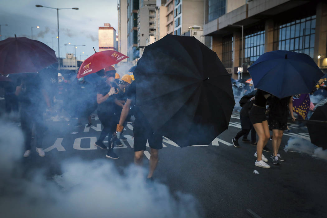 Protesters use umbrellas to shield themselves from tear gas as they face off with riot policeme ...