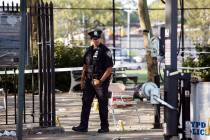A police officer walks by yellow evidence markers at a playground in the Brownsville neighborho ...