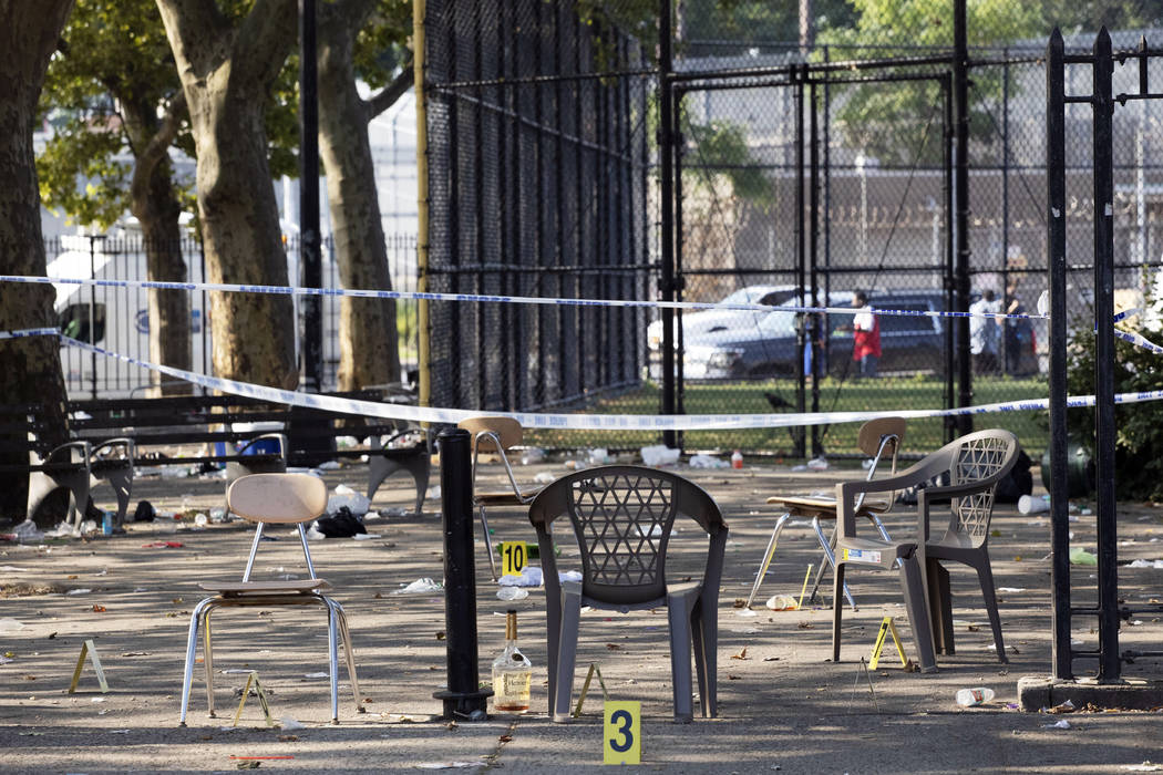 Yellow evidence markers are placed next to chairs at a playground in the Brownsville neighborho ...