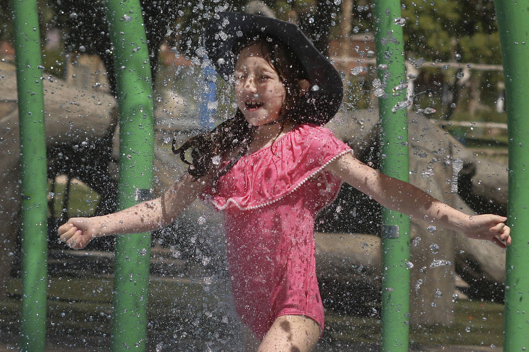 Elle Edwards, 7, cools herself as she plays at Sunset Park during a hot morning on Monday, July ...