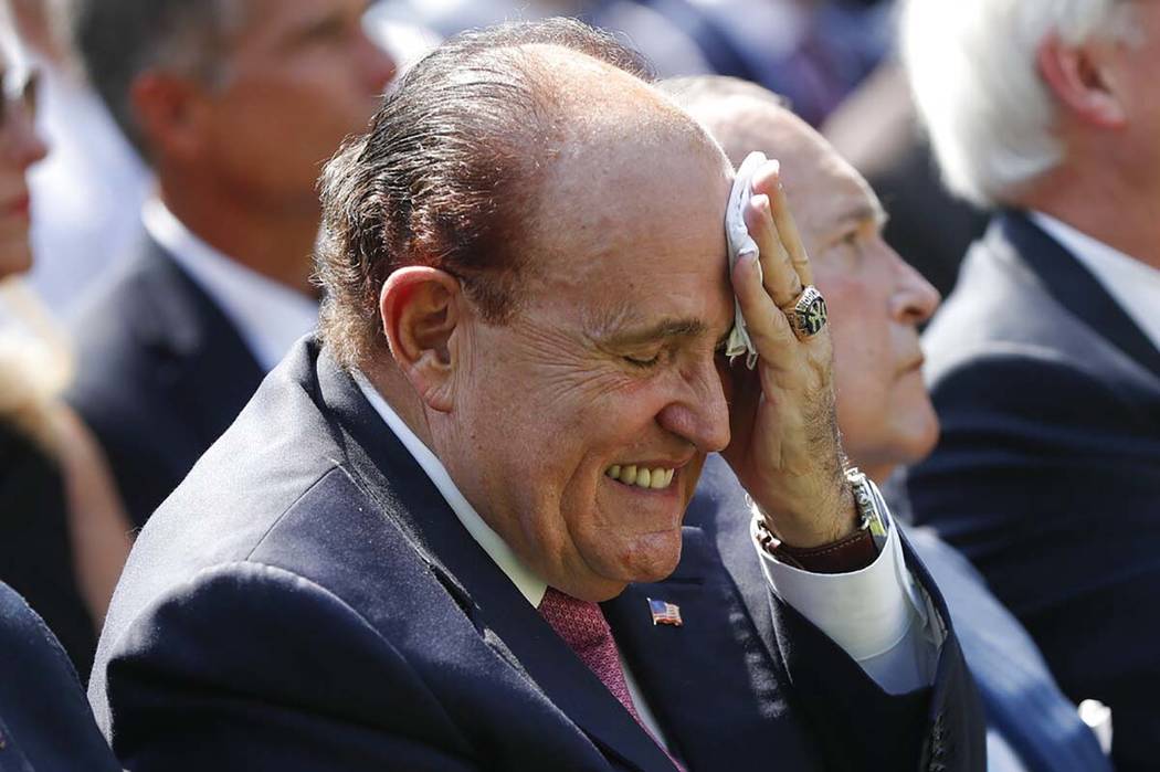 Rudy Giuliani, an attorney for President Donald Trump, left, wipes his forehead as he listens t ...