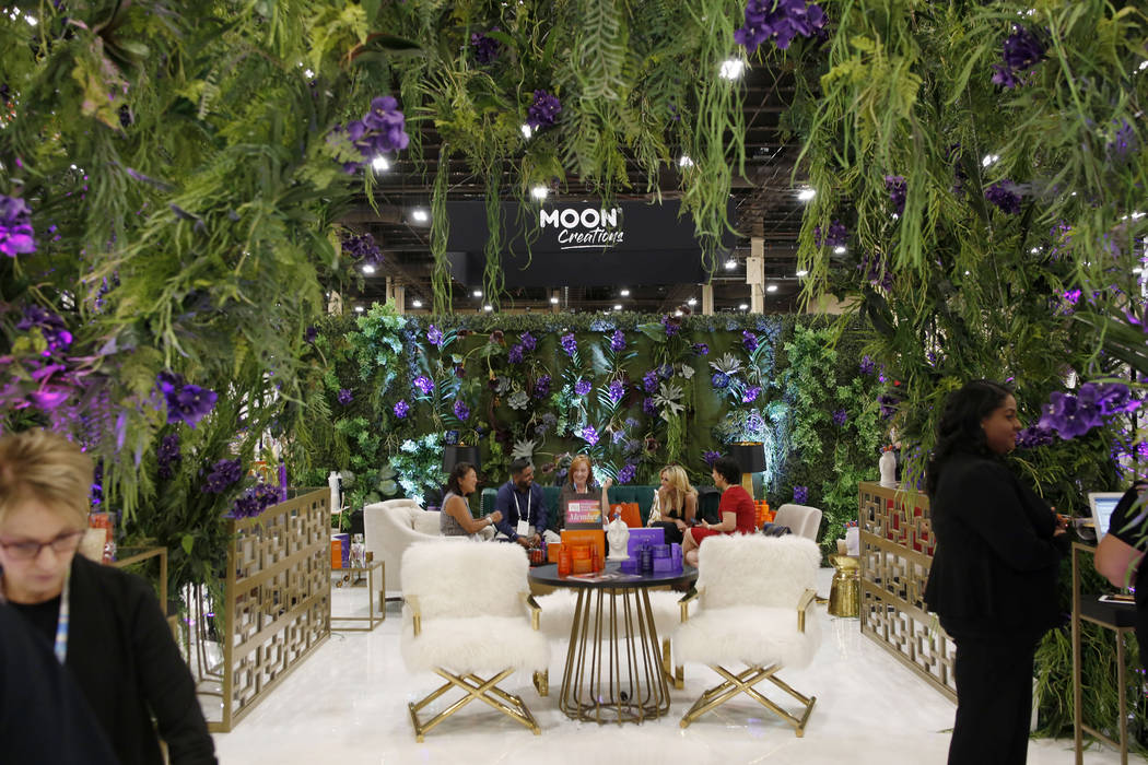 Individuals discuss Obliphica Professional products at their booth at Cosmoprof North America a ...
