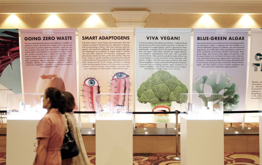 Individuals walk passed a Cosmo Trends banner discussing ethical, vegan and earth conscious pro ...