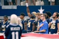 Then-Los Angeles Rams linebacker Robert Quinn (94) raises his fist during the playing of the na ...