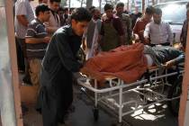 Afghans assist a wounded man in a hospital after a roadside bomb on the main highway between th ...