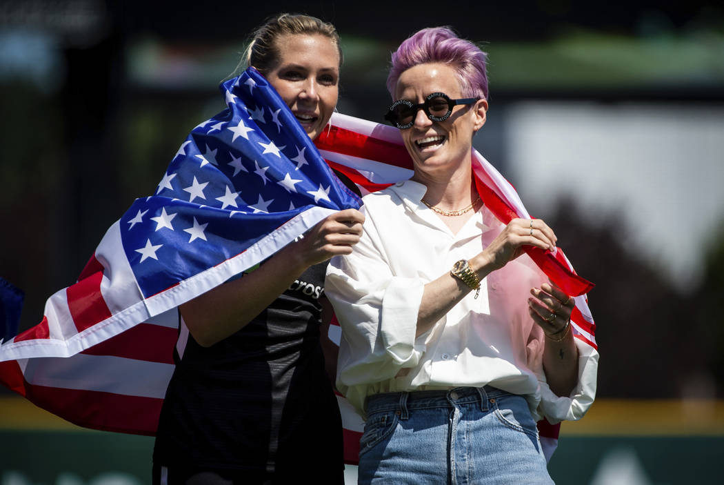 Reign FC midfielder Allie Long, left, and forward Megan Rapinoe, right, wrap themselves in an A ...