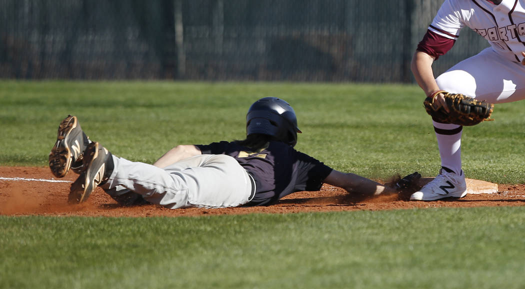 Faith Lutheran’s Paulshawn Pasqualotto (2) dives for first base during a high school b ...