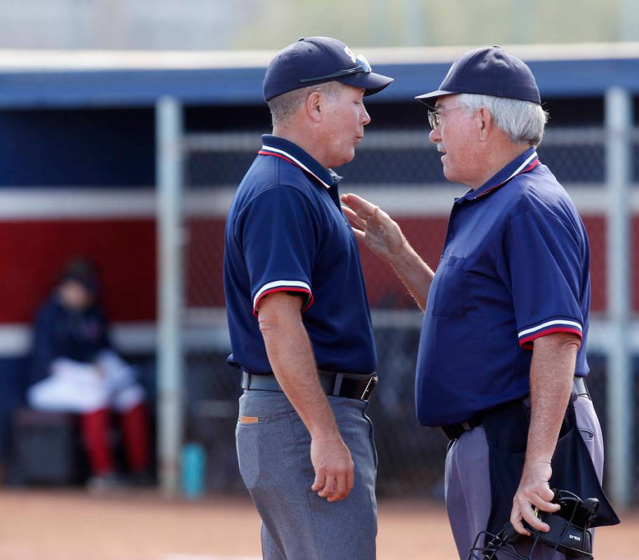 Referees discuss a call during the fourth inning of a high school softball game at Coronado ...