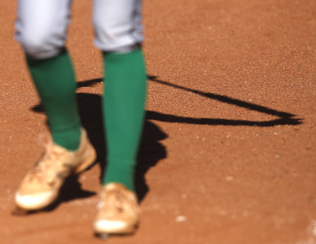 The shadow of a Palo Verde athlete is seen as she stretches before her turn at bat during th ...