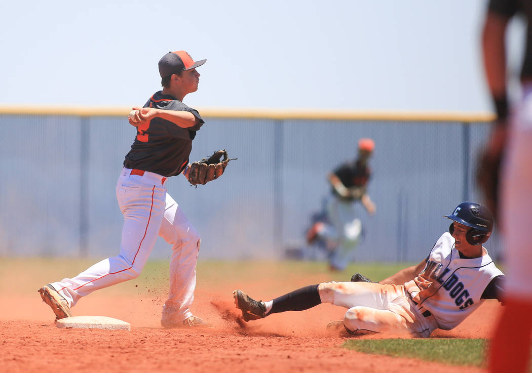 Bishop Gorman short stop Tyler Curtis (2) turns a double play over Centennial baserunner Gin ...