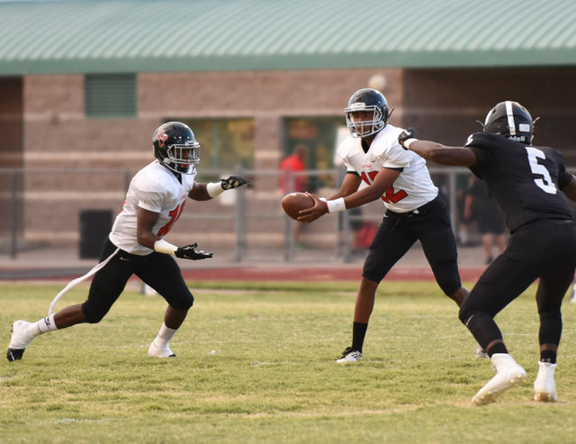 Las Vegas High School’s Zach Matlock (12) hands off the football to teammate Elijah Hi ...