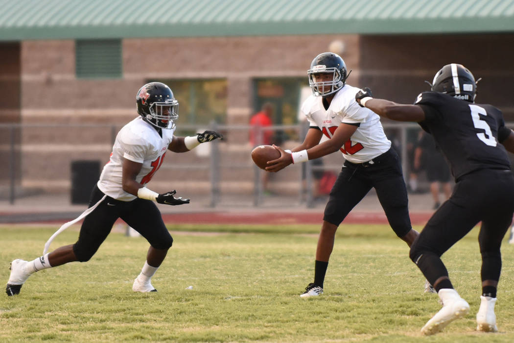 Las Vegas High School’s Zach Matlock (12) hands off the football to teammate Elijah Hi ...
