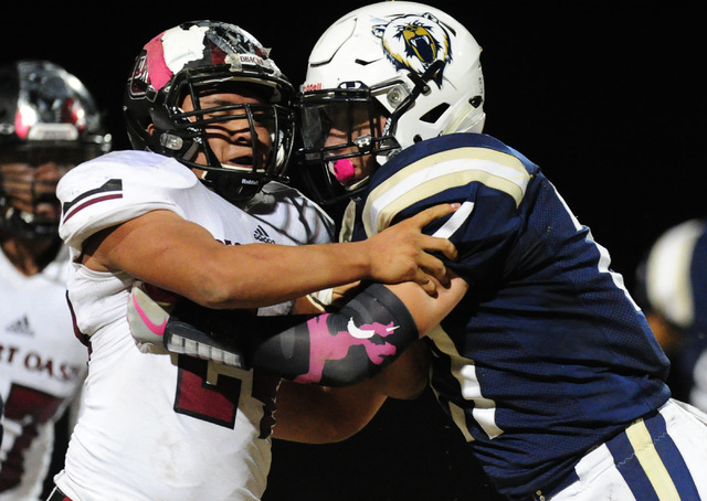 Spring Valley linebacker Clark Genneken, right, pushes Desert Oasis running back Yeyro Guzma ...