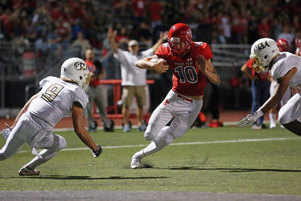 Arbor View quarterback Logan Bollinger, center, attempts to office a tackle from Faith Luthe ...