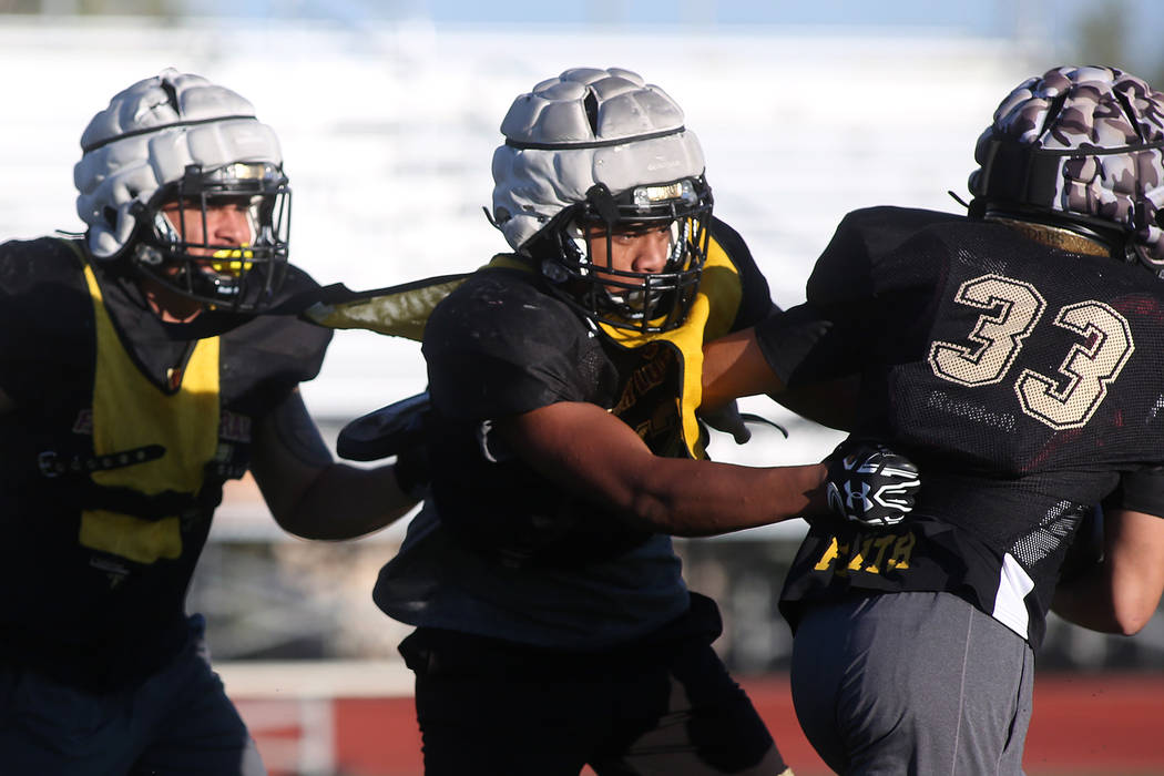 Faith Lutheran football player Ma’a Gaoteote, center, attempts to take down teammate C ...
