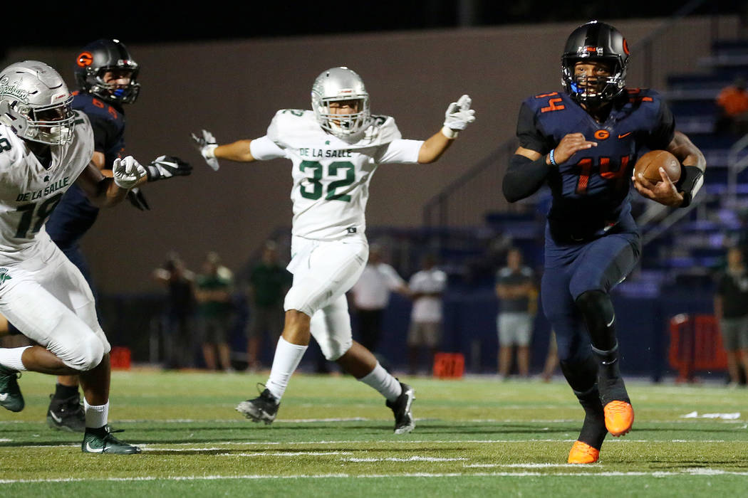 Bishop Gorman’s Dorian Thompson-Robinson (14) runs the ball as he avoids tackles from ...