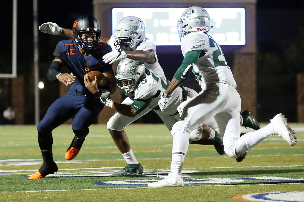 Bishop Gorman’s Dorian Thompson-Robinson (14) runs the ball as he avoids tackles from ...