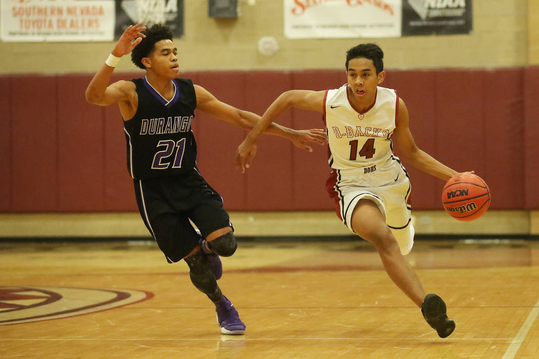 Durango player Anthony Hunter (21) trails after Desert Oasis player Nate Van (14) as he driv ...