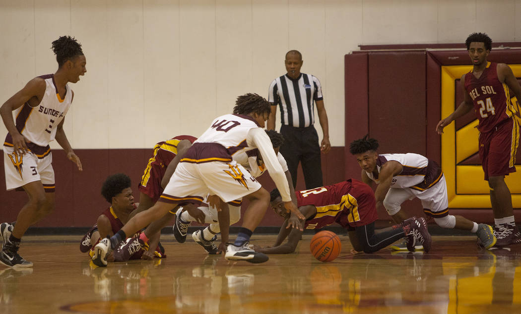 Players of Del Sol High School and Eldorado High School try to catch a dropped basketball in ...