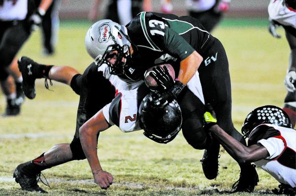 Green Valley’s Kyler Chavez (13) is tackled by Las Vegas defender Jacob Littlefield (2 ...