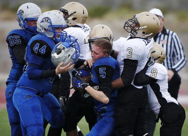 Pahranagat Valley’s Wade Leavitt (5) is wrapped up as his helmet flies off and is caug ...