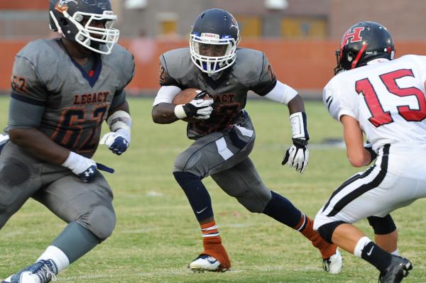 Legacy running back DeMichael Walker (22) looks for running room between offensive lineman E ...