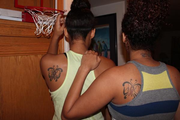 Sisters Paris, left, and Paige Strawther display tattoos designed in honor their late m ...