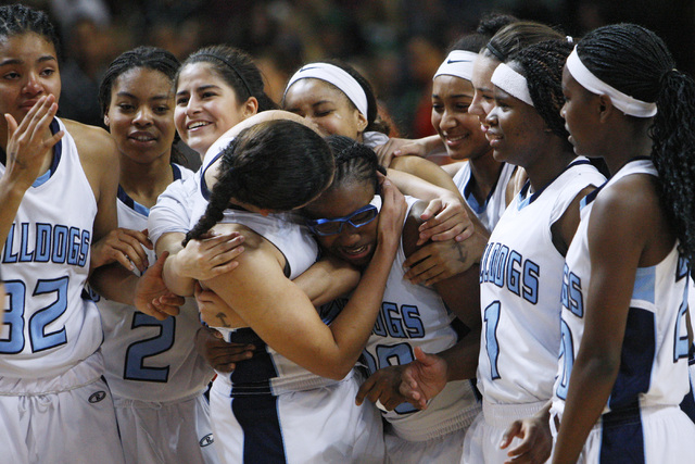 Tanjanae Wells (00) gets a hug as the Centennial girls basketball team celebrates its 65-52 ...