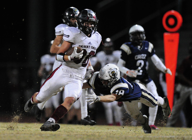 Desert running back Yeyro Guzman, left, rushes past Spring Valley safety Spencer Johnson in ...