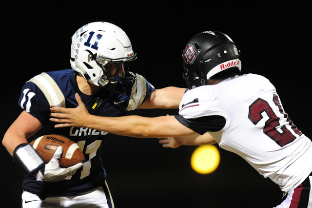 Spring Valley wide receiver Kash Jenkins (11) is tackled by Desert Oasis safety Blake Ricka ...