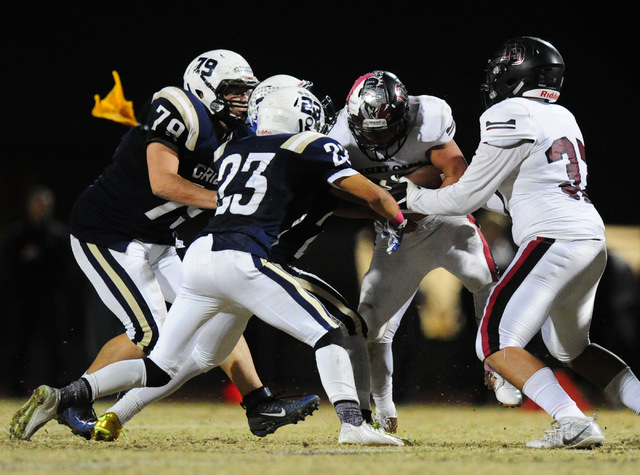 Desert Oasis running back Yeyro Guzman, middle, looks for running room while being tackled b ...