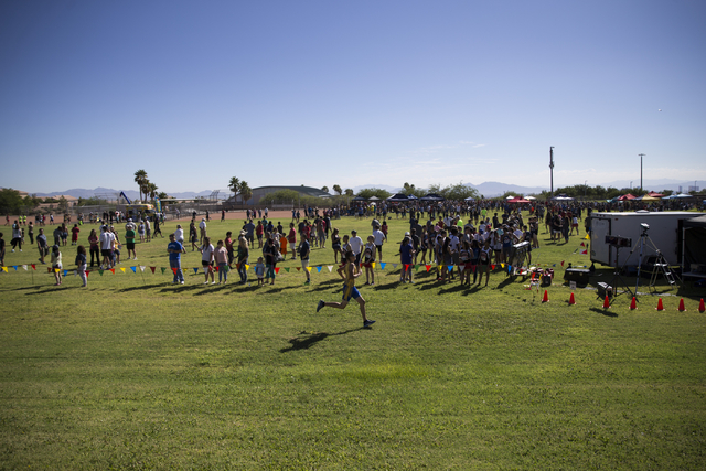 A boys varsity runner is cheered as he runs to the finish line in the cross country Palo Ver ...