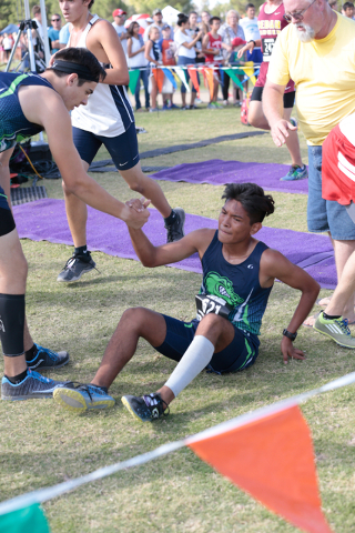 Green Valley’s Jesus Narciso (621) is helped up at the finish line of the varsity A bo ...