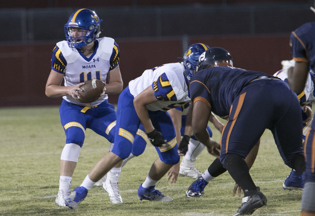 Moapa Valley quarterback Daxton Longman, left, looks for a pass against Legacy High players ...