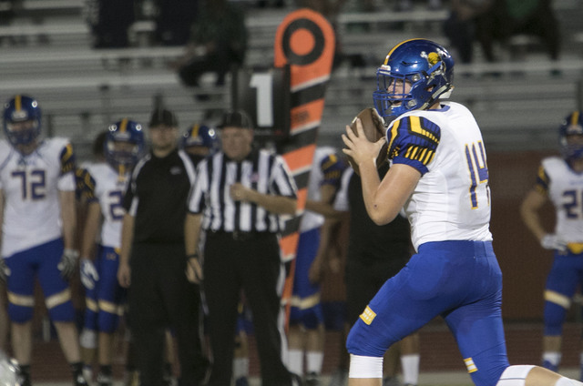 Moapa Valley quarterback Daxton Longman (14) looks for a pass against Legacy High players du ...