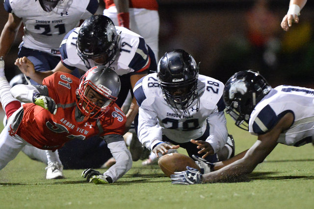 Players dive for a loose football during the Arbor View High School Shadow Ridge High School ...