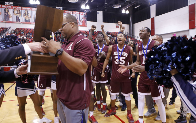 Agassi Prep head coach Trevor Diggs, left, accepts the state championship trophy as his play ...