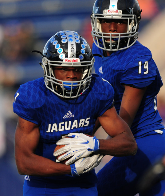 Desert Pines running back Isaiah Morris takes the handoff from quarterback Tyler Williamson ...