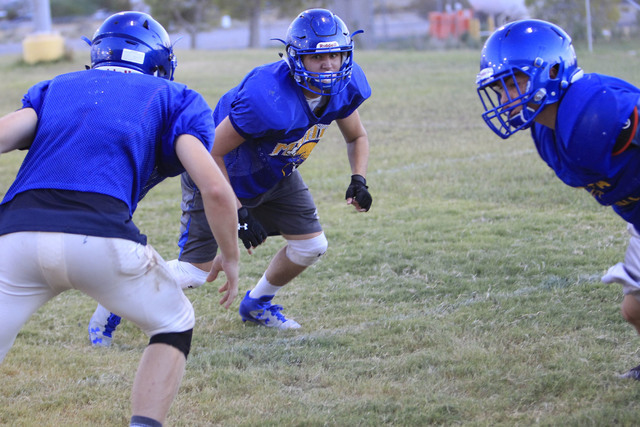 Moapa Valley High School center Cameron Larsen, center, runs through a drill during team pra ...