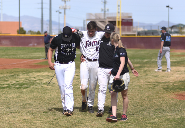 Faith Lutheran’s Brandon Davis (8) is helped off the field by coaches and training sta ...