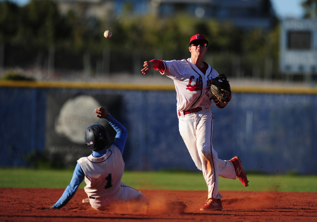 Liberty shortstop Jacob Rogers turns a double play while Centennial base runner Cole Moreno ...