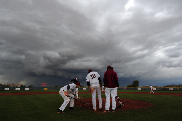 Desert Oasis players rake the pitching mound as a thunderstorm approaches after their prep b ...