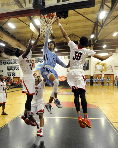 Canyon Springs guard Zaahid Muhammad, center, goes up for a layup while being guarded by Las ...