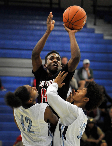 Las Vegas’ Deshawn Weathers, center, shoots over Canyon Springs’ Maurice Hunter ...