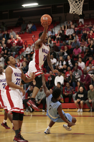 Valley senior Cameron Burton (10) drives up and over Canyon Springs senior Antonio Longmyers ...