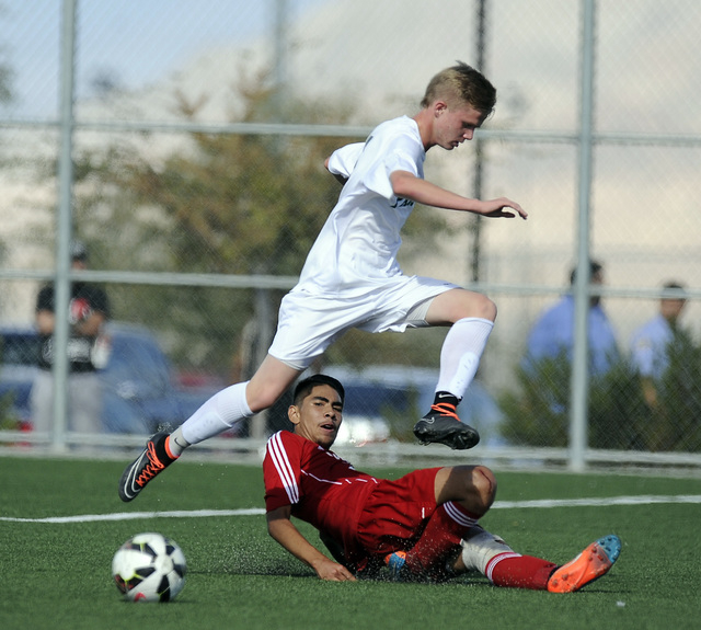 Palo Verde striker Presten Manthey jumps over the slide tackle of Valley defender Steve Fave ...