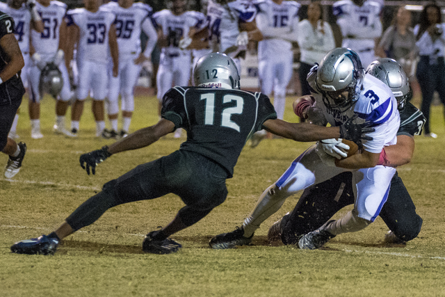 Silverado wide receiver Anthony Bugay (3) is tackled by Green Valley defenders Israel Robins ...