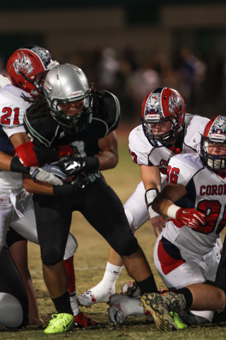 Green Valley’s Brenan Adams (3) holds onto the ball while being tackled by Coronado&#8 ...